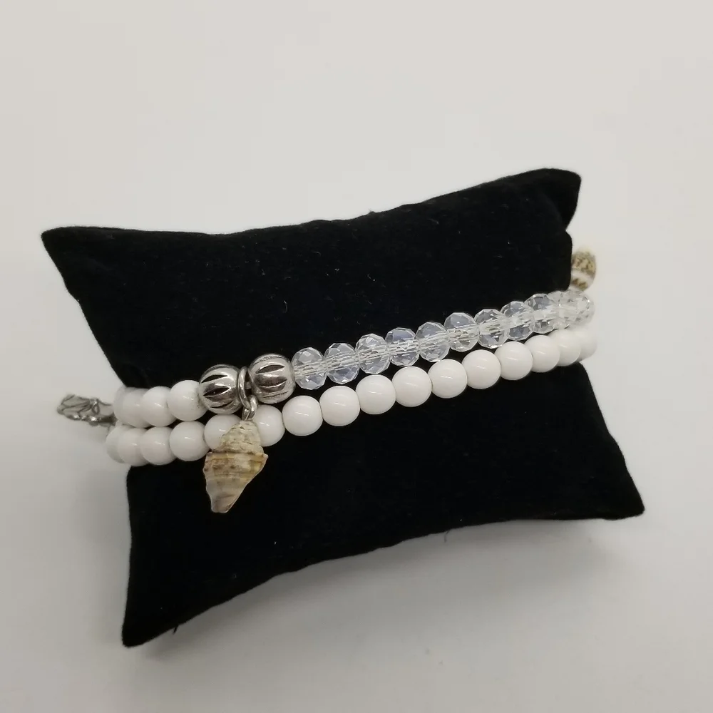 pair of white and clear stretch bracelets with shell charms